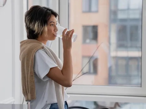 Kadın serinlemek için pencere kenarında su içiyor
